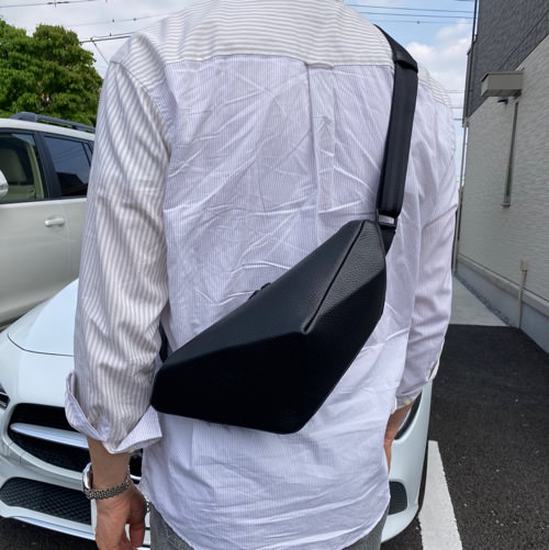 白シャツを着た男性が背中にレザーボディバッグ メンズ用BLACKを着用している写真