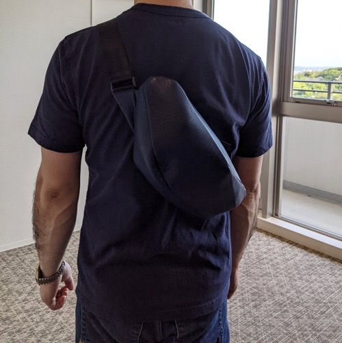 Tシャツを着た男性が背中にレザーボディバッグ メンズ用NAVYを着用している写真