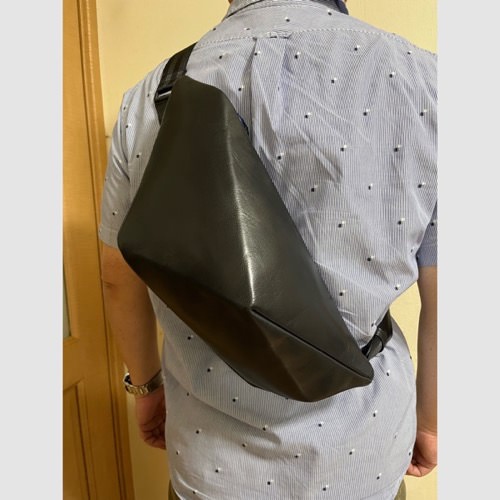 半袖シャツを着た男性が背中にレザーボディバッグ メンズ用CRISTAL NAVYを着用している写真