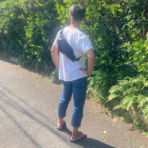 Tシャツを着た男性が背中にレザーボディバッグ メンズ用CRISTAL NAVYを着用している写真