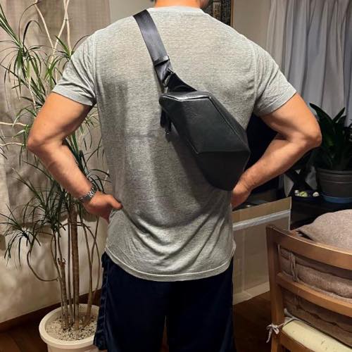 Tシャツを着た男性が背中にレザーボディバッグ メンズ用CRISTAL BLACKを着用している写真