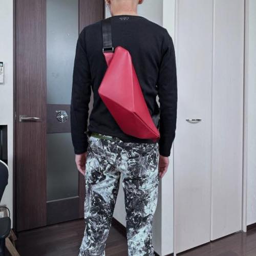 黒の長袖シャツを着た男性が背中にレザーボディバッグ メンズ用REDを着用している写真