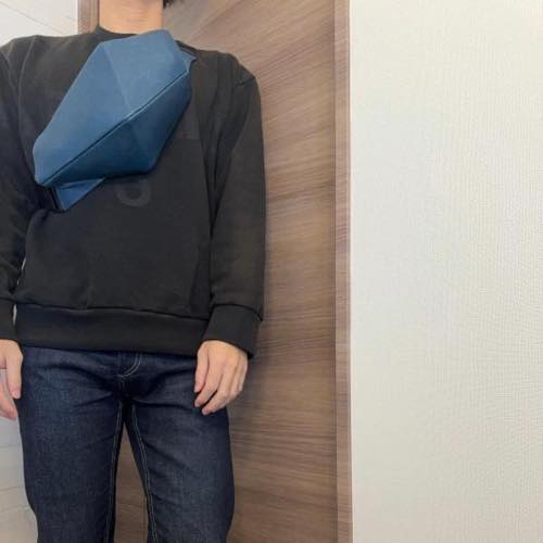 トレーナーを着た男性が胸の前にレザーボディバッグ メンズ用COBALTを着用している写真