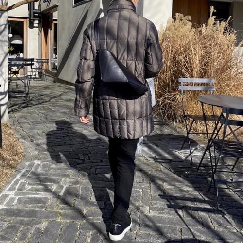カッパー色のダウンコートを着た男性が背中にレザーボディバッグ メンズ用CRISTAL BLACKを着用している写真
