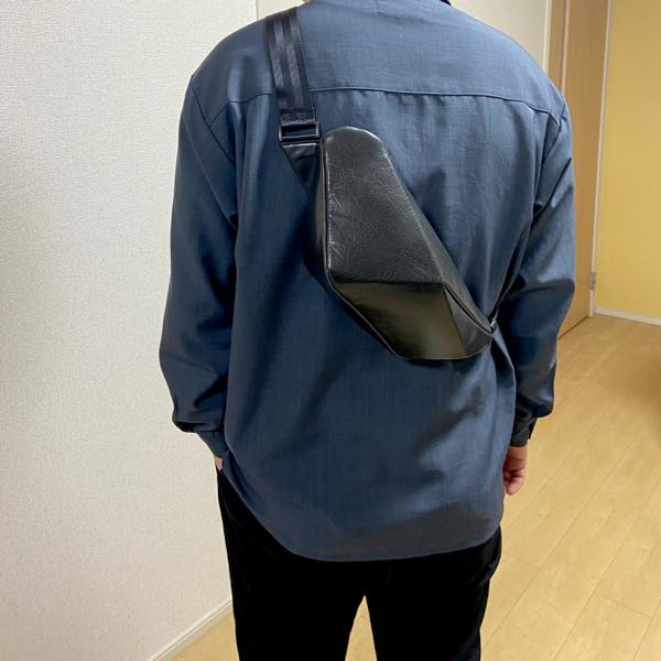 青いシャツを着た男性が背中にレザーボディバッグ メンズ用CRISTAL NAVYを着用している写真